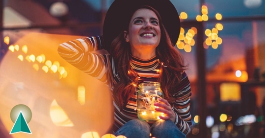 Young female sitting outside holding holiday lights